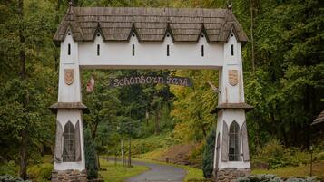 Um arco de madeira branca com a inscrição "Schönborn Park" que dá entrada a uma área arborizada.