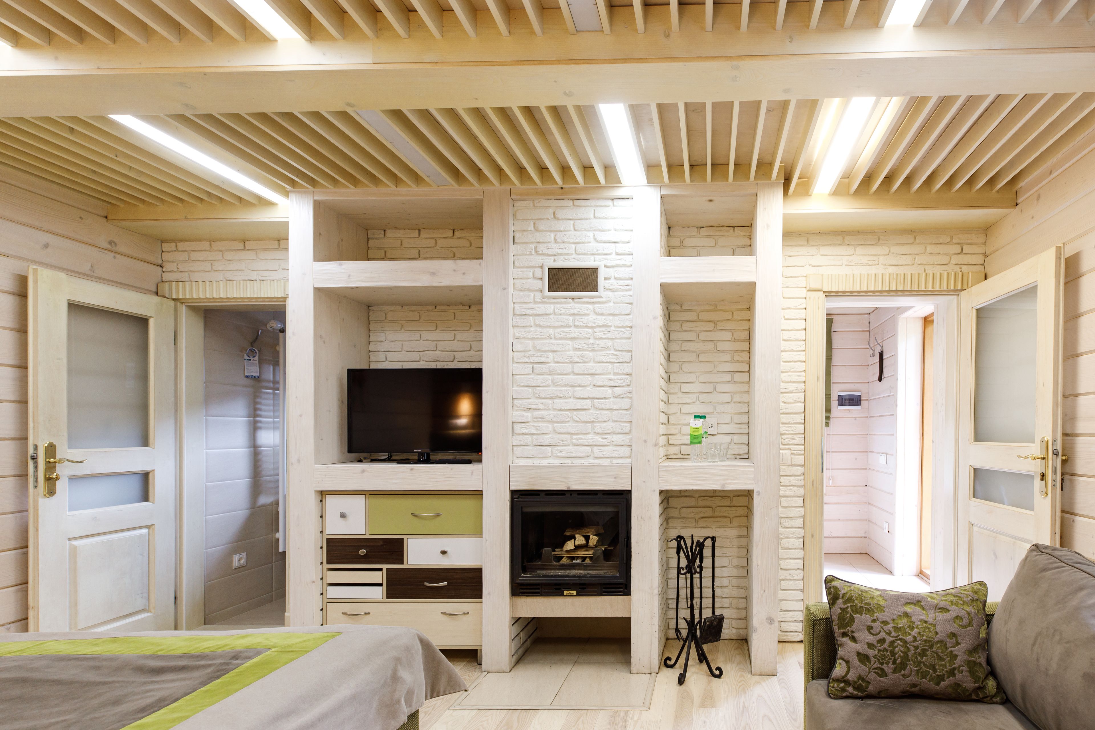Ein Zimmer mit eingebautem Kamin, Holzbalken an der Decke und einem Fernseher auf einem Regal.