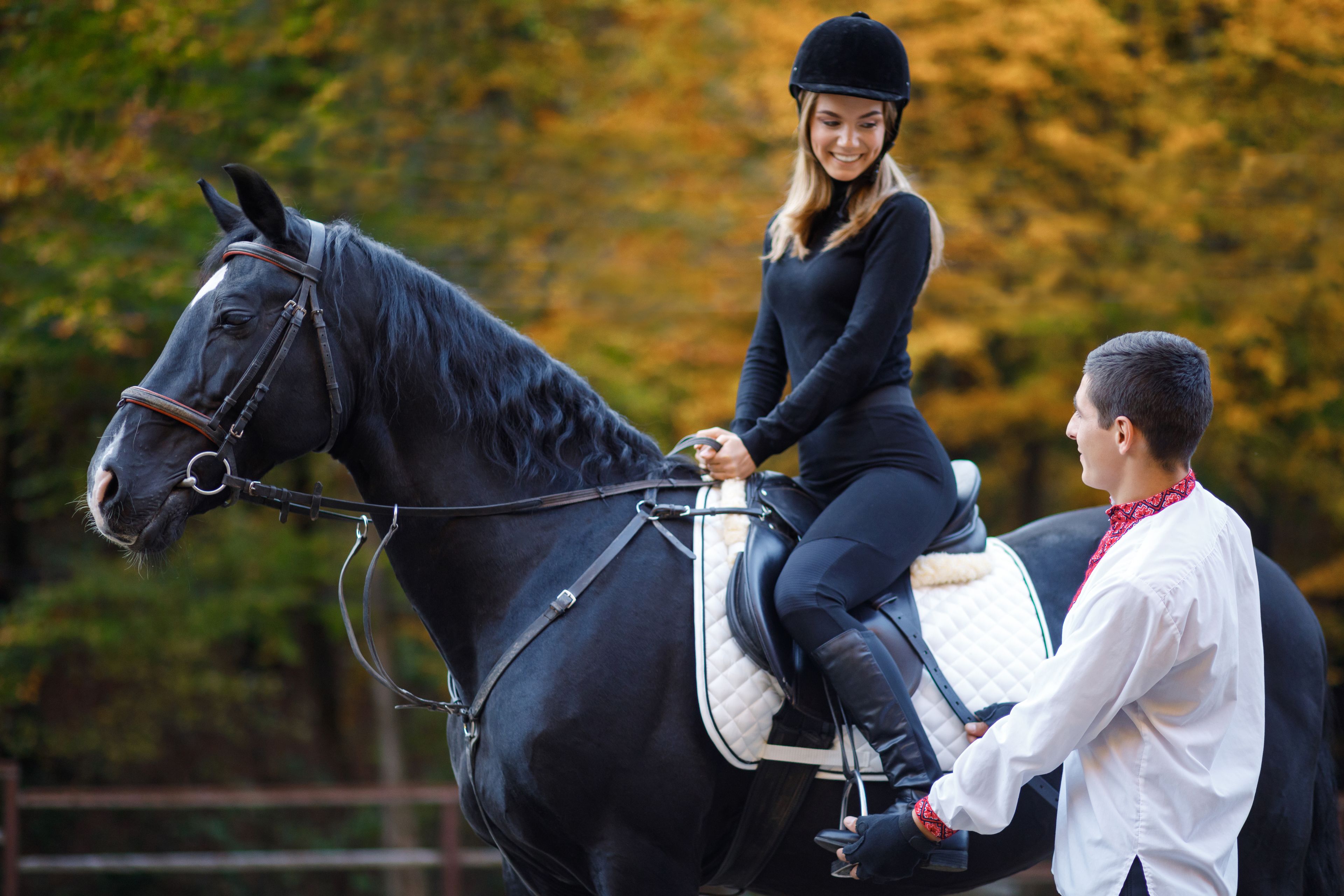A person riding a horse in an outdoor setting with trees in the background.