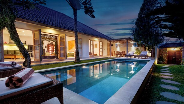 Ein modernes Haus mit Swimmingpool, Außenbereich zum Sitzen und einem gut beleuchteten Innenraum.