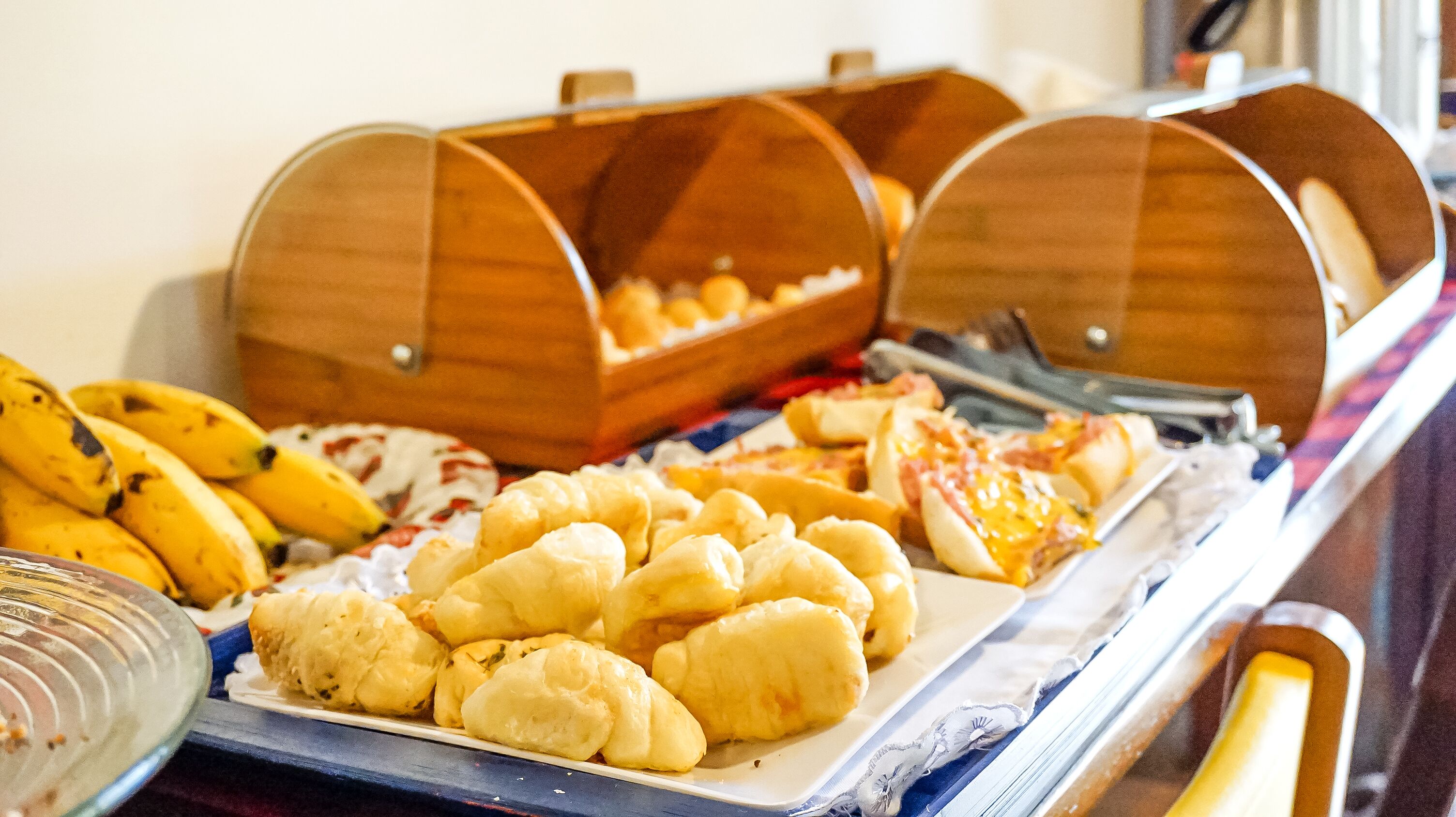 Een buffet met diverse gerechten, waaronder bananen, broodjes en gebak.