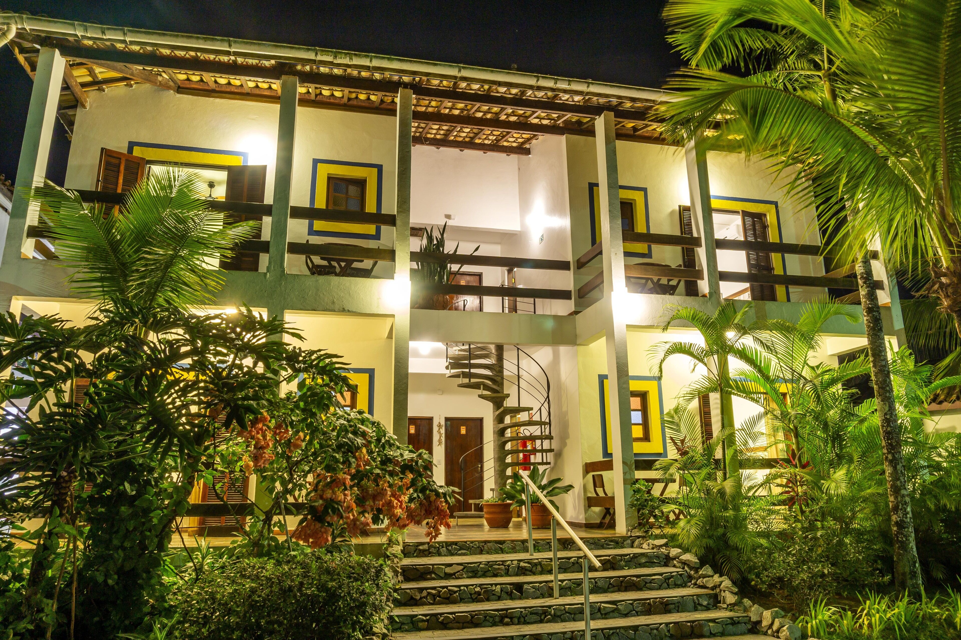 A two-story building with a central staircase, balconies, and surrounding greenery.