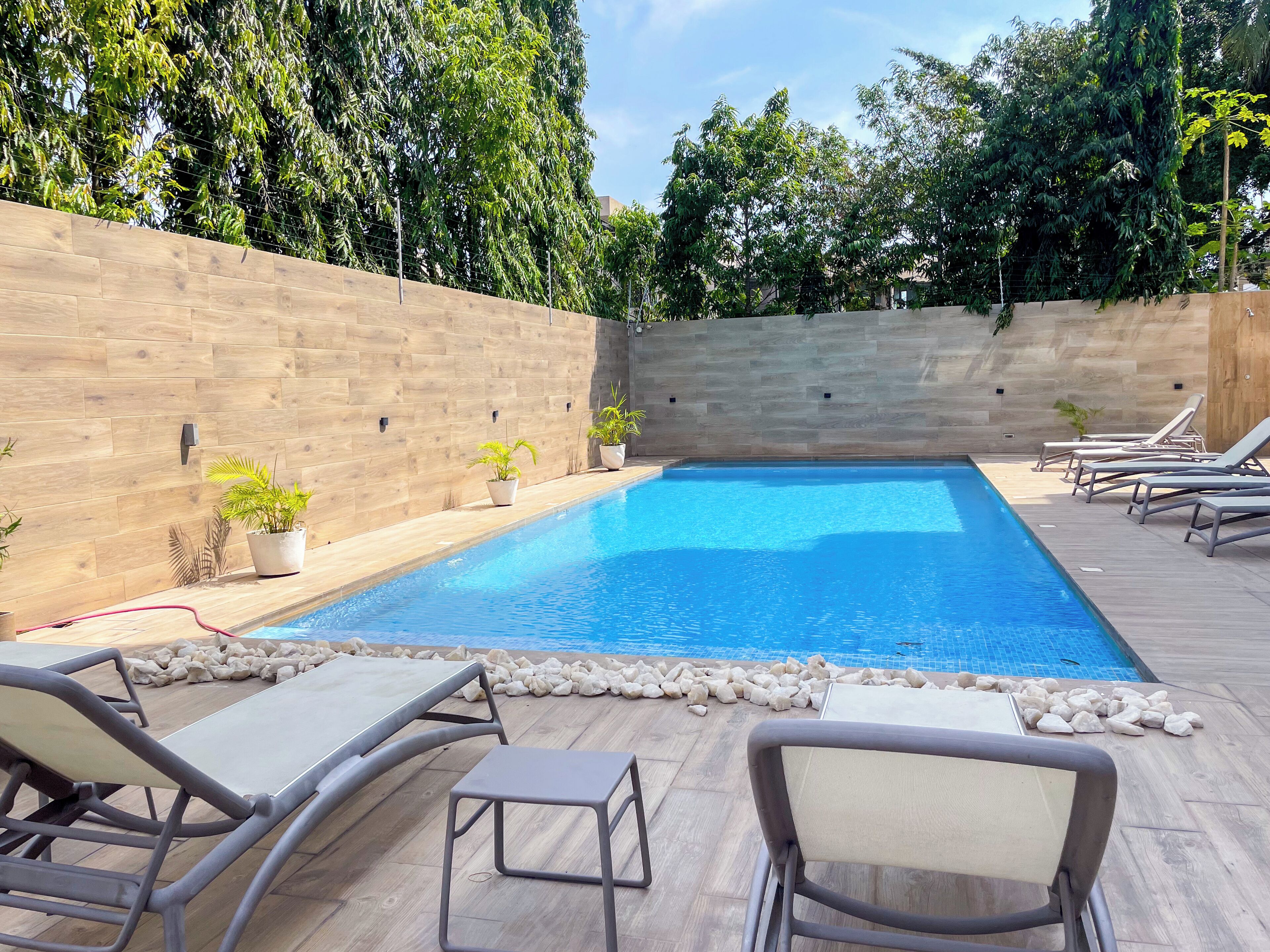 Una piscina con sillones de descanso y plantas en macetas.