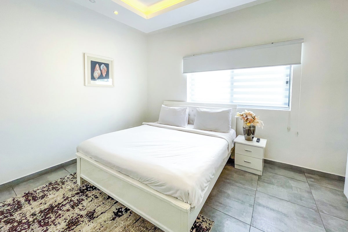 Une chambre à coucher avec un lit, une table de chevet et une fenêtre avec des stores.