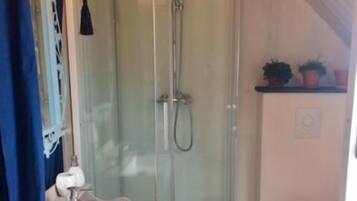 A bathroom with a glass-enclosed shower, a white sink, and a toilet.
