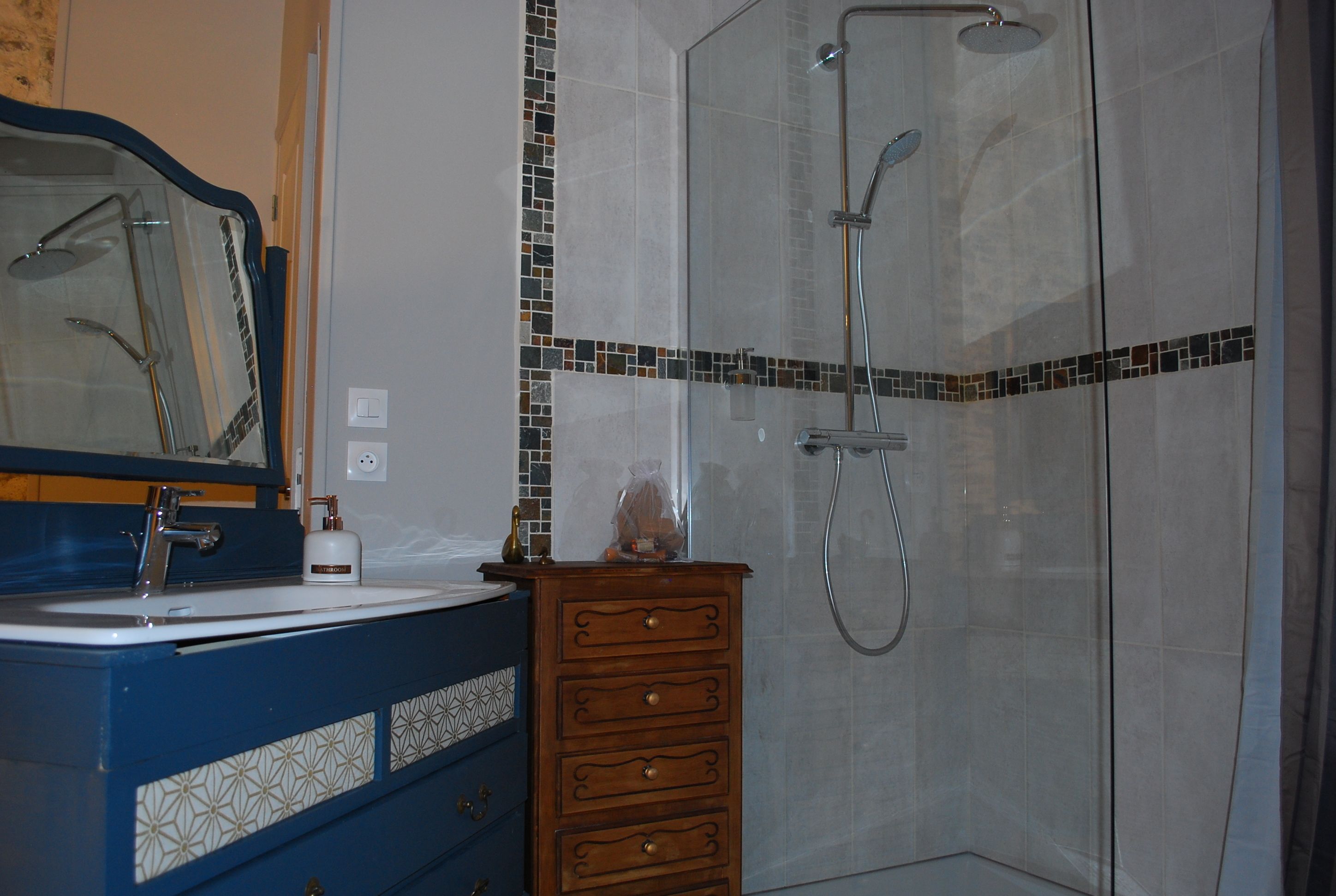 A bathroom with a sink, mirror, and shower.