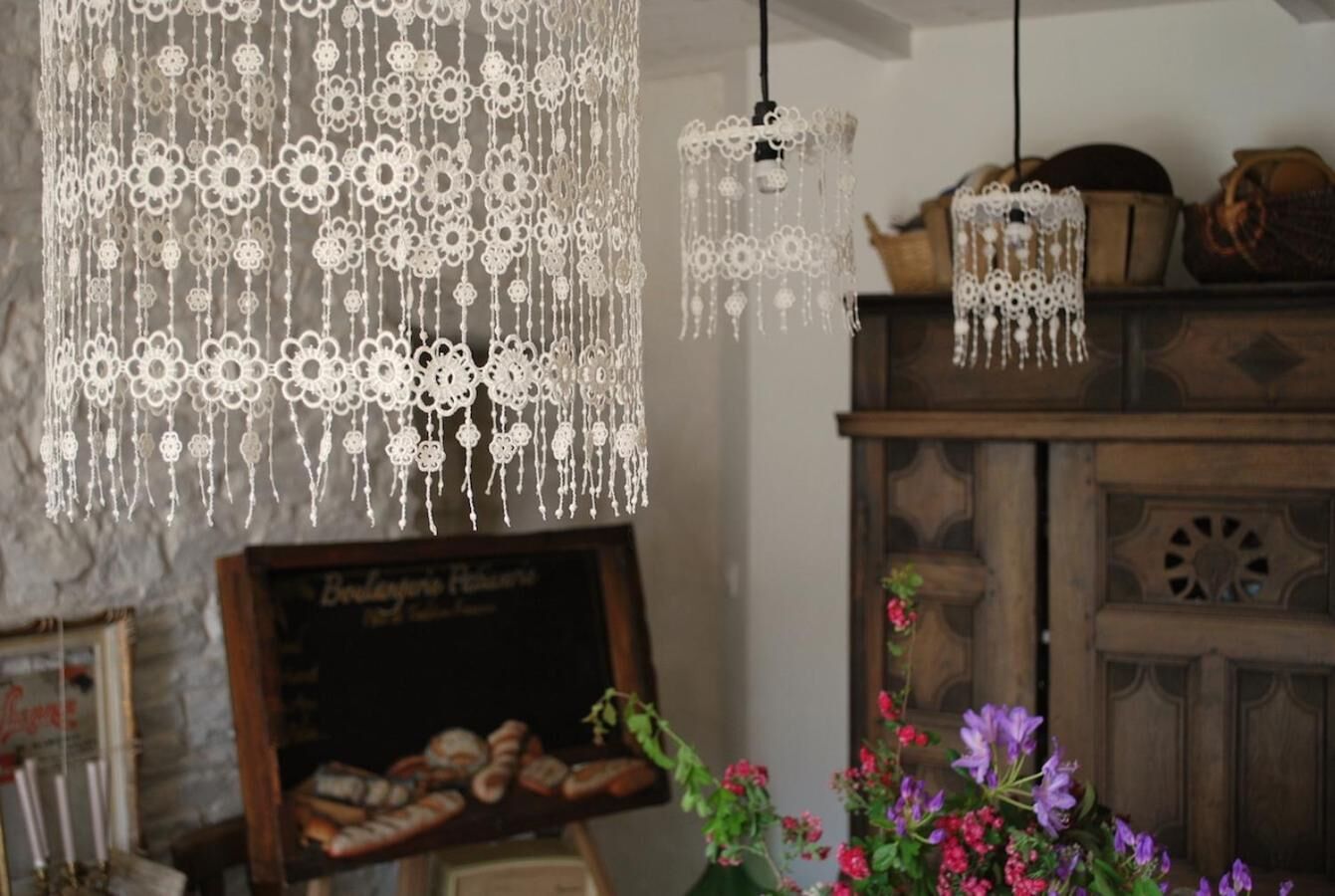 A rustic interior with lace chandeliers, a chalkboard menu, and wooden furniture.