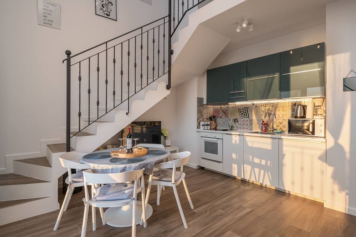 Eine moderne Küche mit Essbereich, inklusive Treppe, Holzboden und zeitgemäßer Kücheneinrichtung.