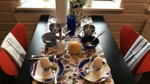 Una mesa de comedor dispuesta con platos, cuencos, cubiertos y un mantel decorativo.