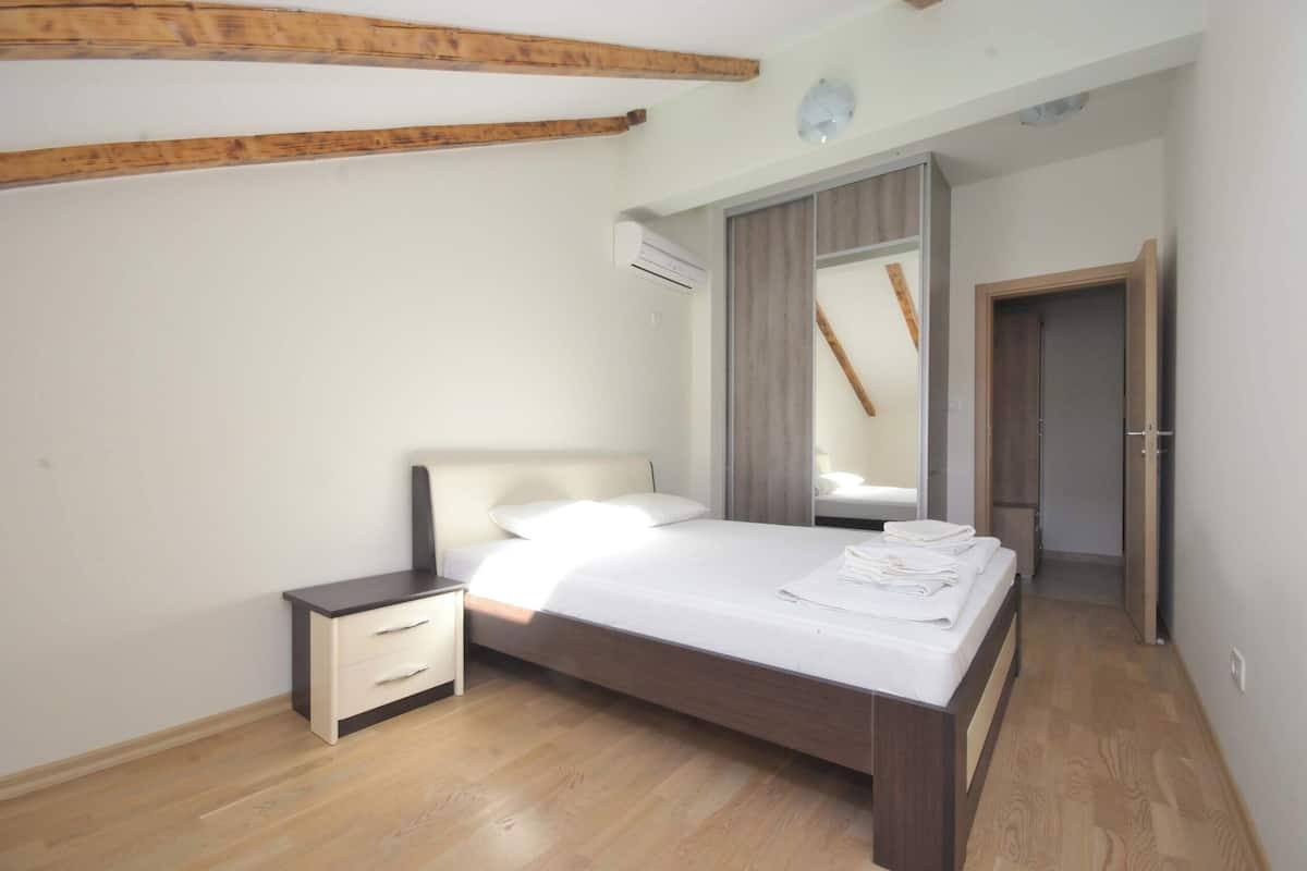 A bedroom with a bed, bedside table, and an air conditioning unit.