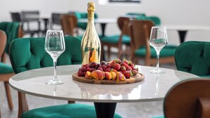 Una mesa redonda con una bandeja de frutas, una botella de champán y dos copas vacías.