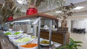 A buffet setup with various food items in bowls, a metal serving station, and potted plants. - Bodrum Moonlight Hotel (Bodrum)