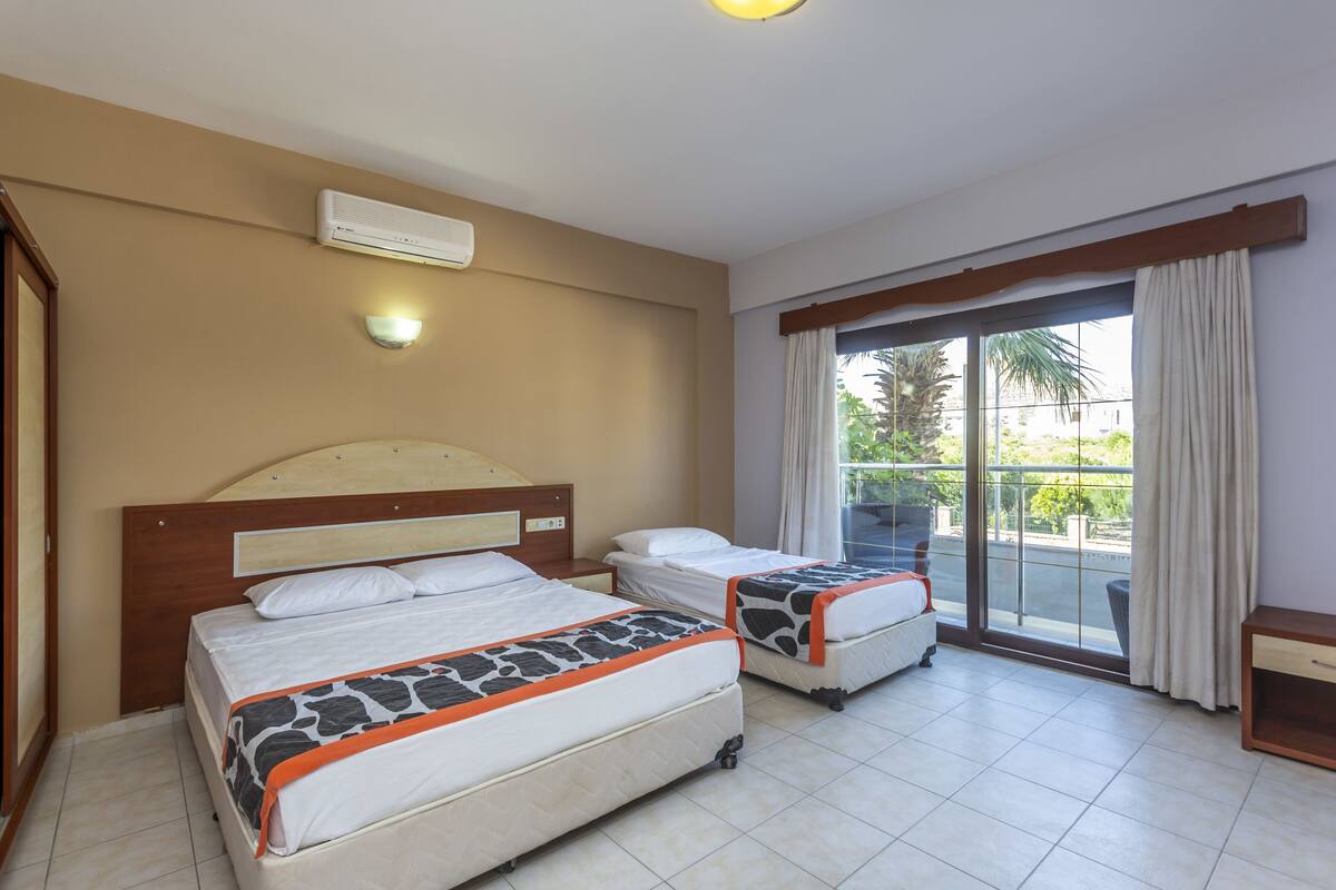 Ein Hotelzimmer mit zwei Betten, einem großen Fenster und einer Klimaanlage.