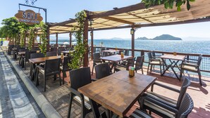 An outdoor dining area with wooden tables and chairs, a sign for 'SALT KITCHEN & LOUNGE', and a view of the sea. - Bodrum Moonlight Hotel (Bodrum)
