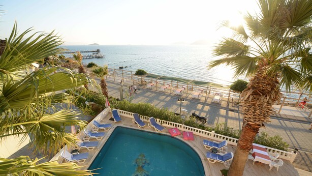 A pool area with lounge chairs and a view of the sea. - Bodrum Moonlight Hotel (Bodrum)