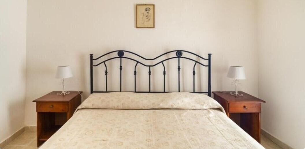 Ein Schlafzimmer mit einem Bett, zwei Nachttischen und einem Wandbild.