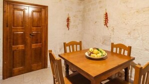 Un coin repas avec une table et des chaises en bois, un saladier rempli de fruits et une porte en bois.