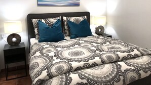 A neatly made bed with patterned bedding, two bedside lamps, and a wall-mounted abstract painting. - Villa Estrella with private pool and hottub in Mazarron (Mazarrón)
