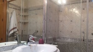 A bathroom with a white sink, a glass shower enclosure, and tiled walls. - Beautiful apartment facing the sea with huge terrace (El Campello)