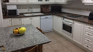 A compact kitchen with white cabinets, a granite countertop, a microwave, a dishwasher, and a stove. - Beautiful apartment facing the sea with huge terrace (El Campello)
