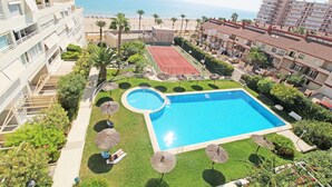 Ett hotell med en swimmingpool, en tennisbana och utsikt över stranden.
