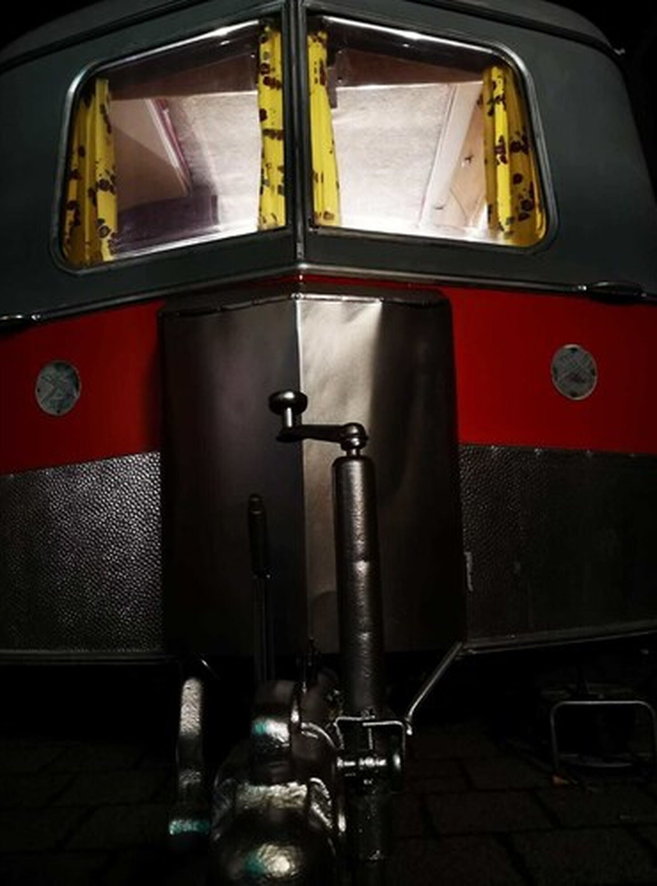 Un autobús antiguo con interior metálico, un volante y un picaporte visible.
