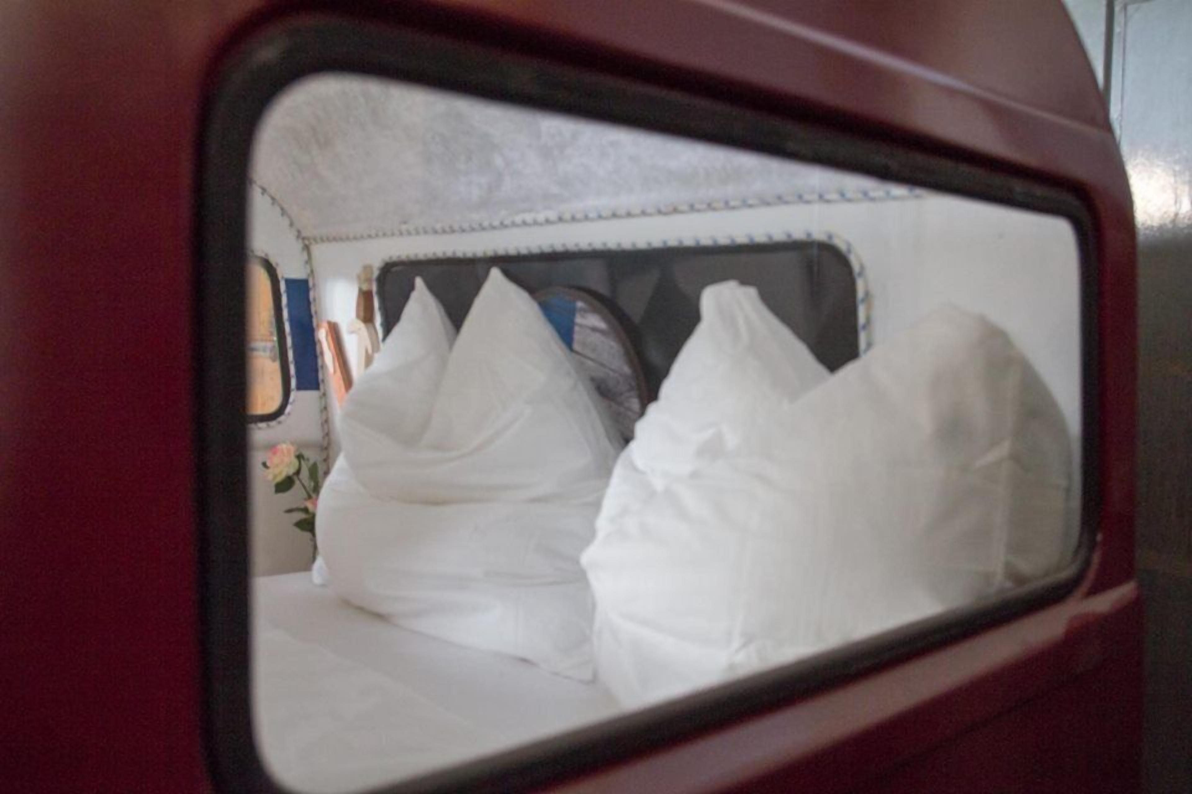 Una cama con almohadillas blancas y un cabecero en una habitación.