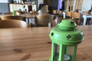 Une lanterne verte ornée de quatre motifs en forme de trèfle, posée sur une table en bois dans un restaurant.
