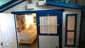 A small, cozy room with a bed, a table with a vase, and a chair. - HafenTraum IndoorHostelCamp (Bremen)
