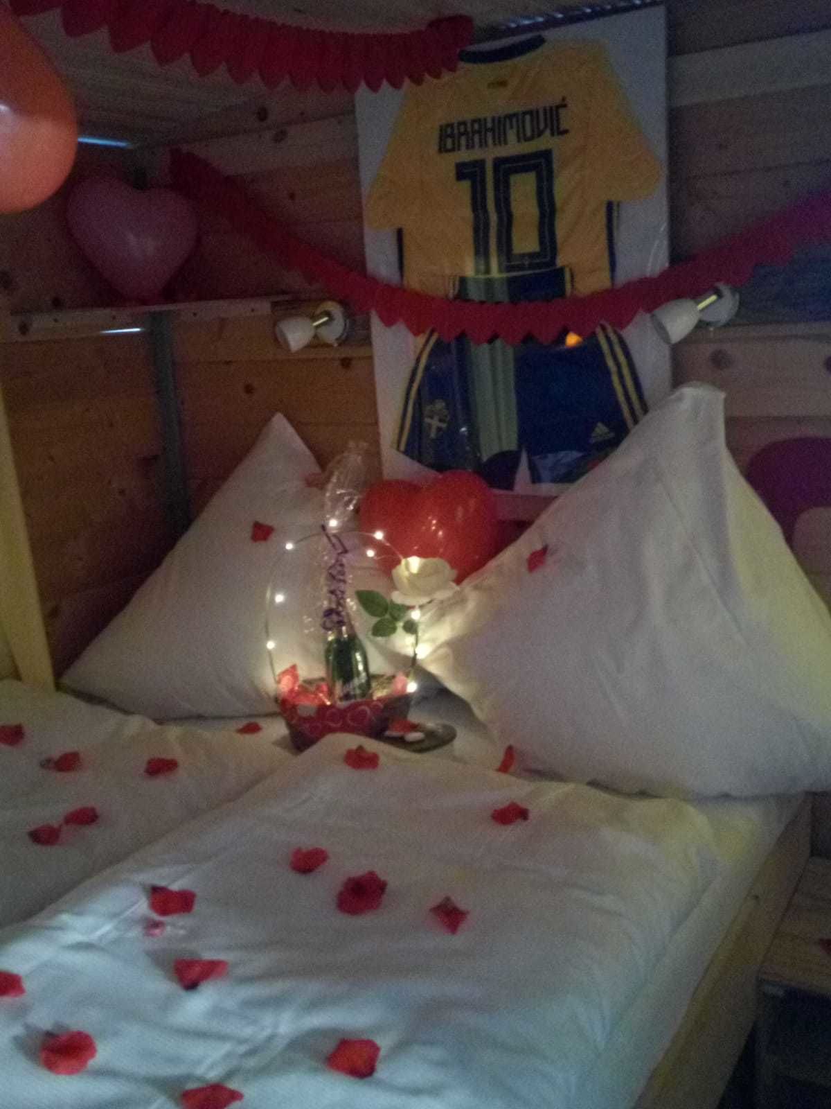 Una cama con pétalos de rosa, una camiseta y una botella.