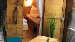 A wooden hut with a sign reading "VIETNAM". Inside, there is a bed, a small table with a plant, and a blue bench. - HafenTraum IndoorHostelCamp (Bremen)