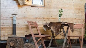 A rustic wooden cabin interior with a metal stove, wooden chairs, and a small table. - HafenTraum IndoorHostelCamp (Bremen)