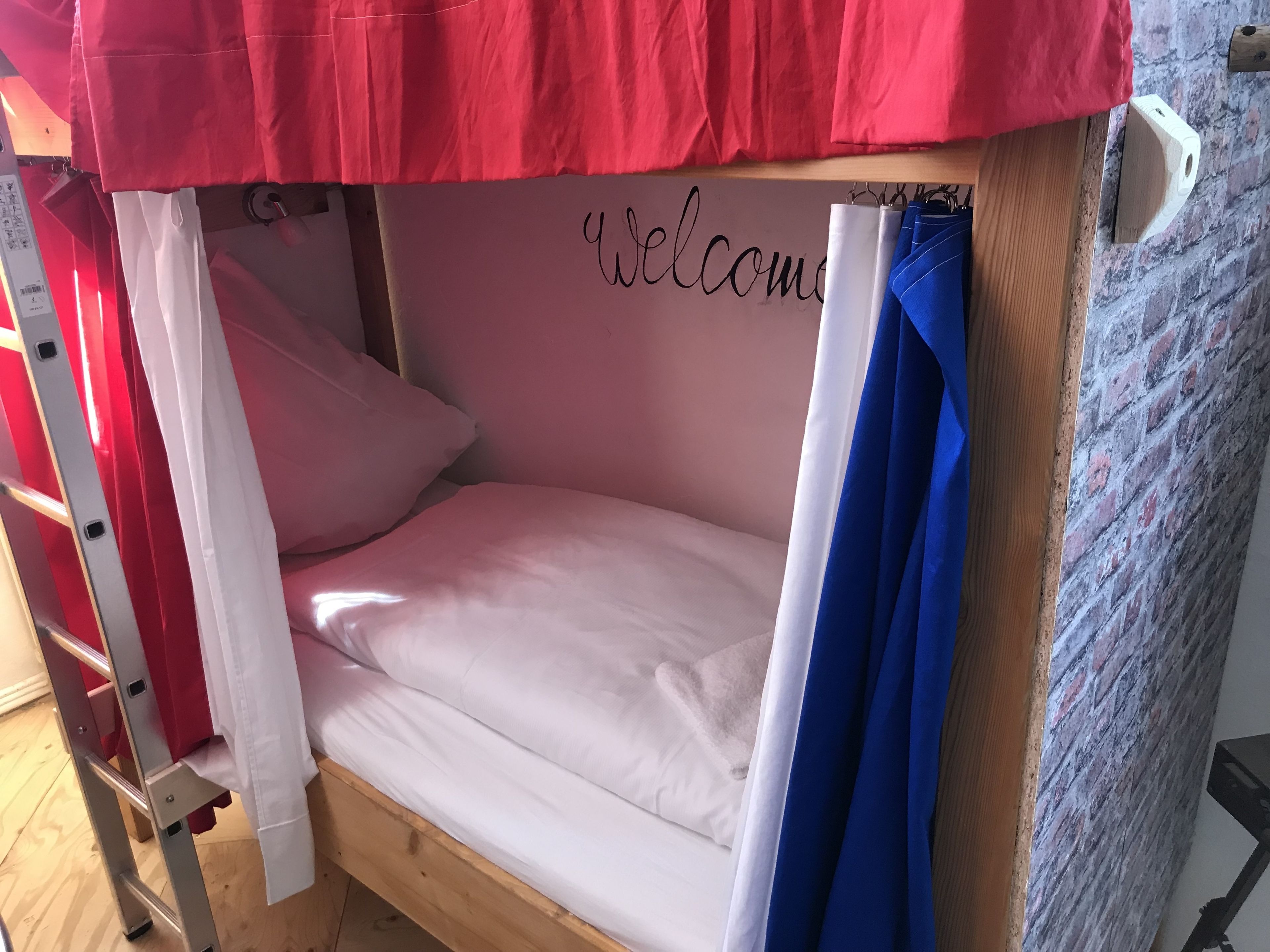 A bunk bed with a 'Welcome' sign, wooden frame, and a ladder.