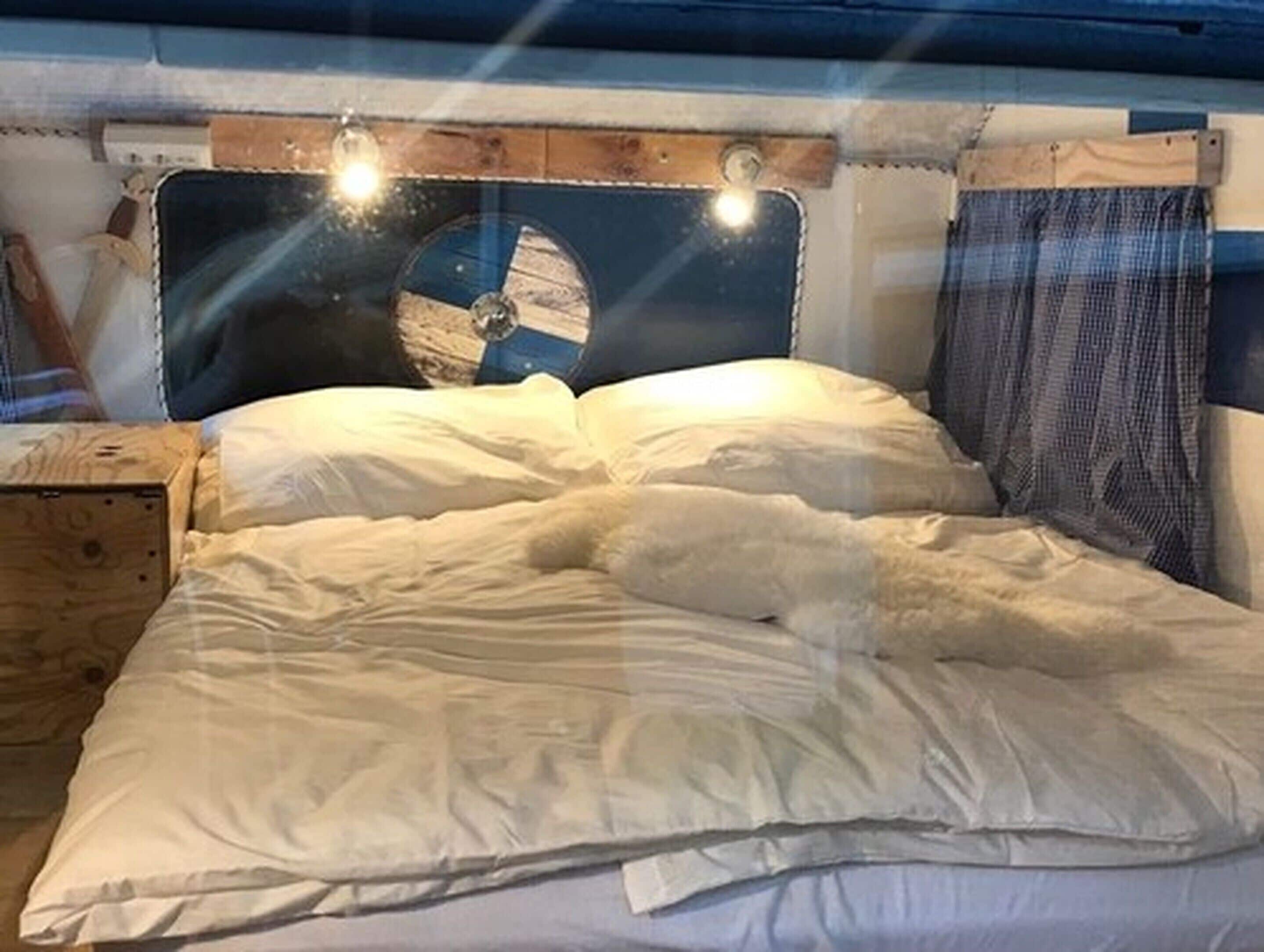 A bed with white linens and a headboard with a blue and white design.