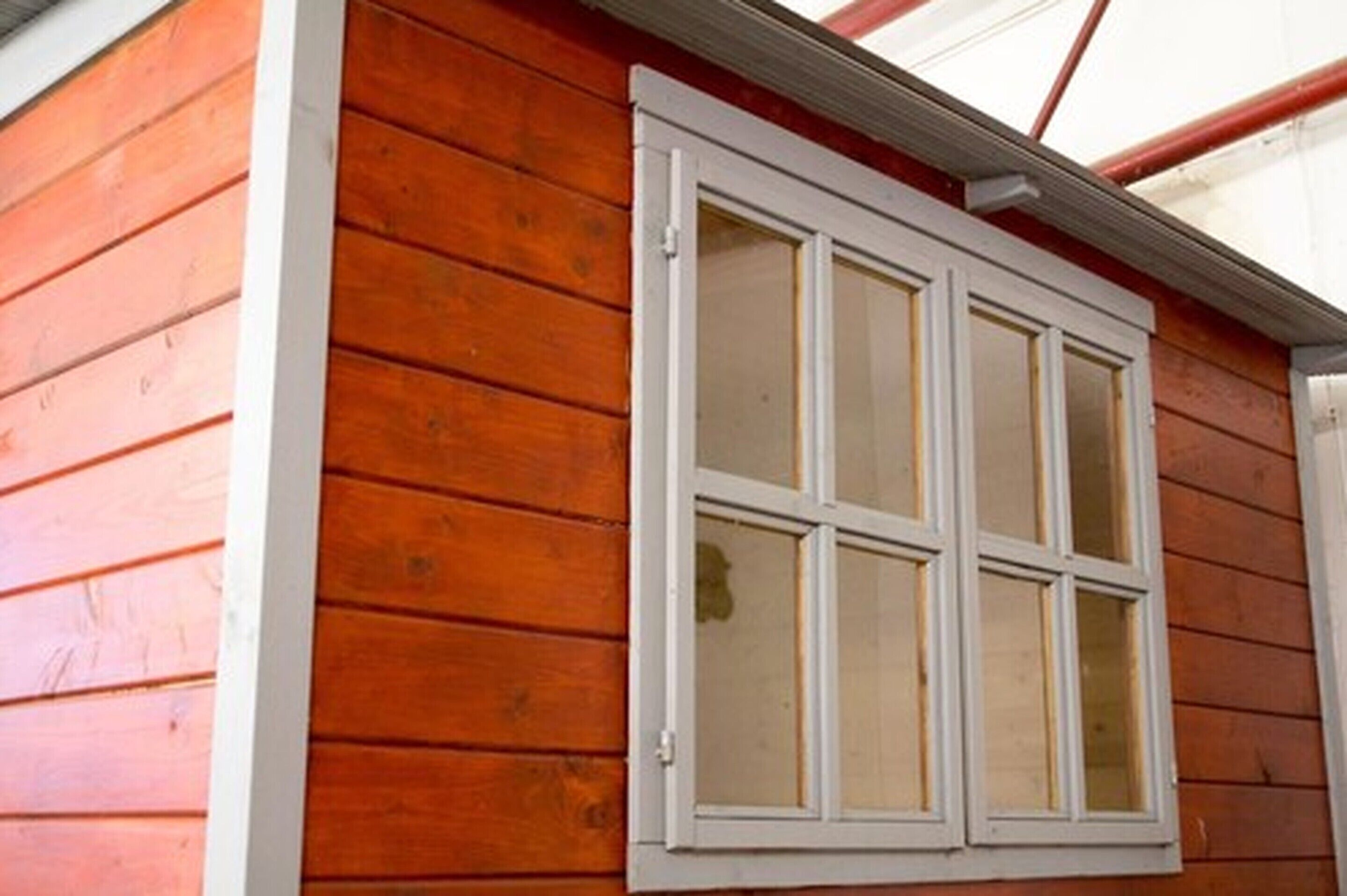 Un mur extérieur en bois avec une fenêtre à cadre blanc.