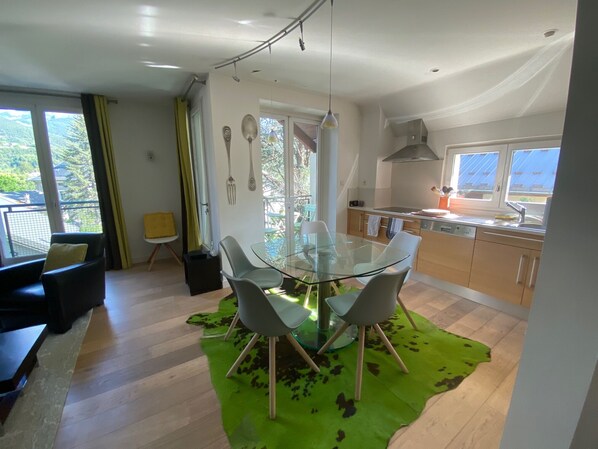 Una cocina moderna con una mesa de comedor de vidrio, armarios de madera y vistas al exterior.