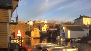 A waterfront dock with several boats moored, wooden buildings, and a clear sky. - Glesvær Rorbu (Oygarden)