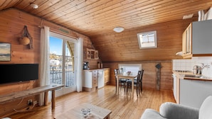 A cozy cabin with wooden floors, a dining area, a kitchen, and a television. - Glesvær Rorbu (Oygarden)