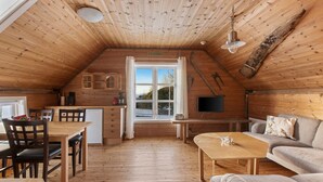 A cozy wooden cabin with a dining area, a sofa, and a TV. - Glesvær Rorbu (Oygarden)