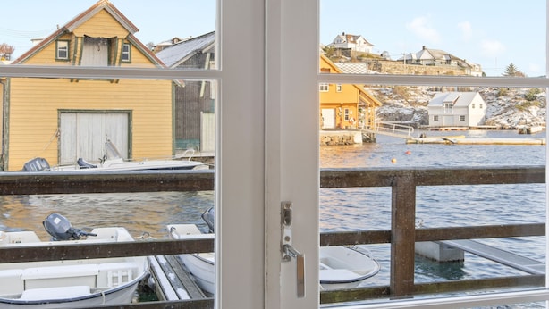 A wooden deck with a view of boats and buildings across the water. - Glesvær Rorbu (Oygarden)