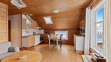 A cozy wooden cabin with a dining area, kitchen, and a large window offering a view.