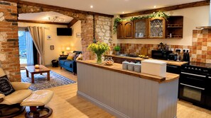 A modern kitchen with a central island, wooden cabinets, and a stone wall.