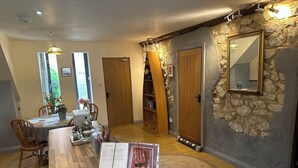 A cozy dining area with a wooden table and chairs, a stone accent wall, and a mirror. - The Old Barn Self Catering Cottage by the Beach, Dog Friendly on Norfolk Coast (Heacham)