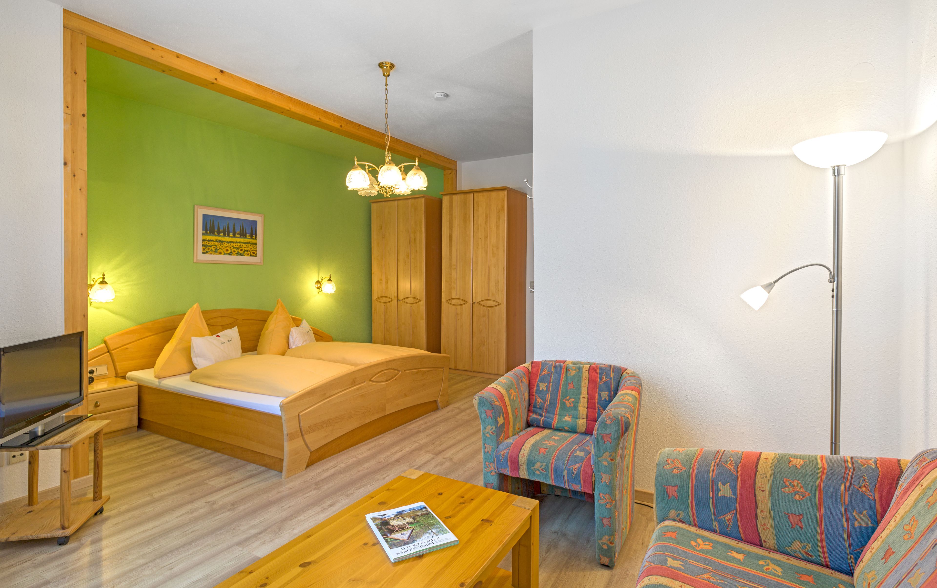Una habitación con una cama, un escritorio de madera, una silla, un sofá y una lámpara.