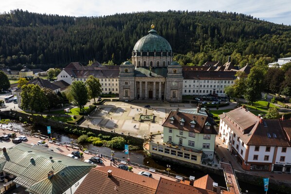 A large historic building with a prominent dome, surrounded by traditional architecture and a river. - Dom Hotel (St. Blasien)