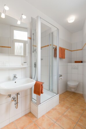 A bathroom with a glass-enclosed shower, a sink, and a toilet. - Dom Hotel (St. Blasien)