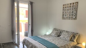 A bedroom with a bed, a nightstand, a wall art piece, and a sliding glass door leading to an outdoor area. - Tulipano House - Key to Villas (La Ciaccia)