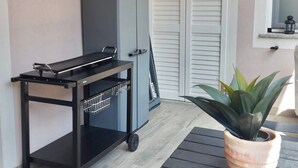 A small, enclosed balcony with a table, a potted plant, and a grey cabinet. - Tulipano House - Key to Villas (La Ciaccia)