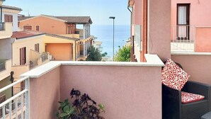 A balcony with a potted plant, a chair, and a table. - Tulipano House - Key to Villas (La Ciaccia)