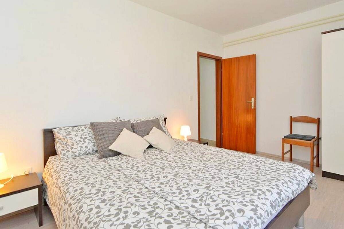 A bedroom with a bed, bedside tables, a chair, and a wardrobe.